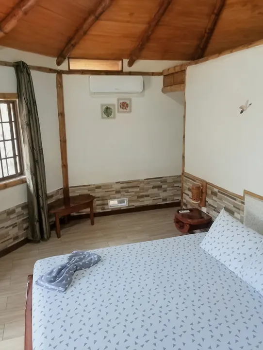 Habitación de la cabaña familiar con aire acondicionado, ventana con cortina, banca de madera y techo de madera