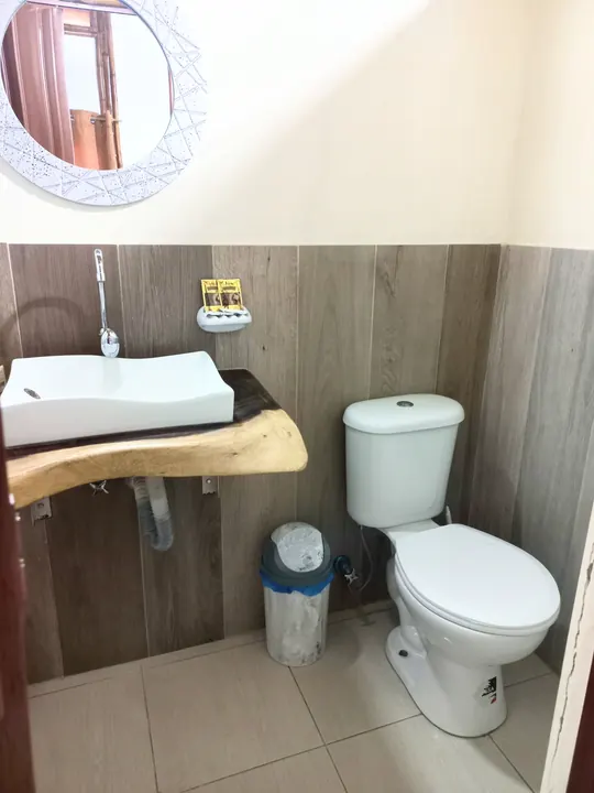Baño de la cabaña familiar 6 con lavabo sobre madera natural, espejo redondo e inodoro