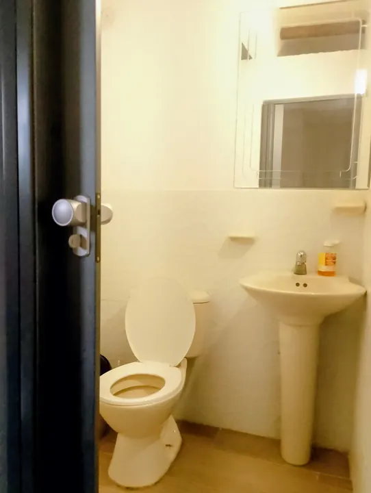 Baño de la suite familiar con inodoro y lavabo de pedestal, visto a través de la puerta abierta