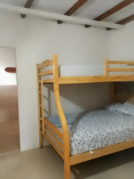 Litera de madera clara con cama doble abajo, cama sencilla arriba y ropa de cama estampada